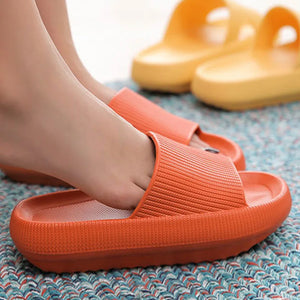 Woman wearing orange cloud slippers on a rug